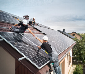 Wall Mural - Men technicians mounting photovoltaic solar moduls on roof of house. Engineers in helmet installing solar panel system outdoors. Concept of alternative and renewable energy. Aerial view.