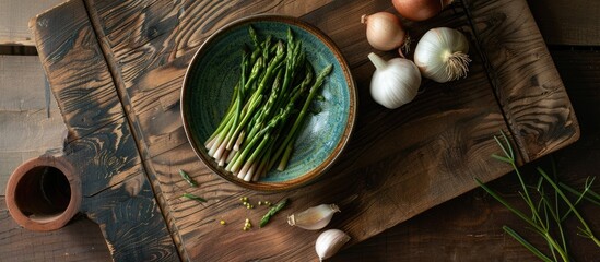 Poster - An aerial photograph of a bowl containing salicornia sea asparagus placed on a wooden cutting board with half an onion and garlic providing copy space image