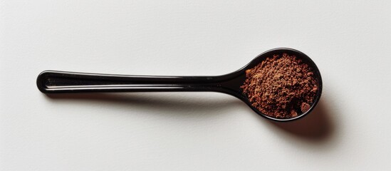 Poster - A black plastic spoon carrying coffee powder is showcased on a white background in a copy space image