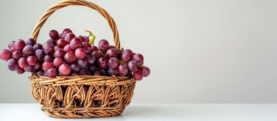 Poster - Vintage wicker basket filled with red grapes on a white background providing copy space image
