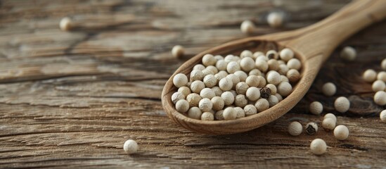 Poster - Organic white pepper corn in a wooden spoon displayed on a rustic wooden surface with a copy space image available