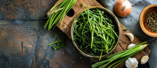 Poster - An aerial photograph of a bowl containing salicornia sea asparagus placed on a wooden cutting board with half an onion and garlic providing copy space image