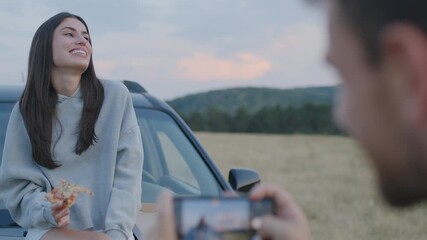 Wall Mural - Man taking a photo with a smartphone of a woman during the road trip in the nature