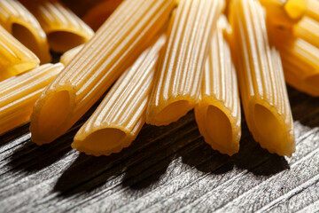 Wall Mural - pasta penne rigate on wood background macro