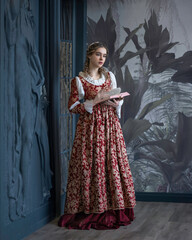 Wall Mural - An aristocratic girl in a vintage dress with a book in a spacious hall