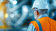 © Oranuch - A construction worker in a safety helmet observes ongoing operations in a modern industrial environment.