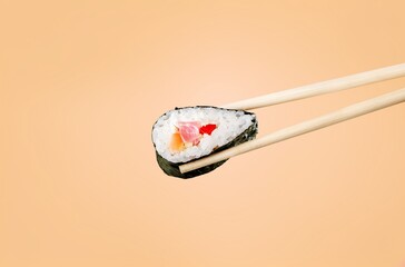 Canvas Print - Fresh tasty sushi roll on chopsticks on background