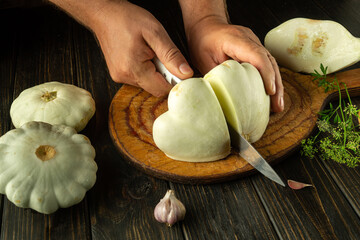 Wall Mural - Cooking zucchini on the kitchen table by a man. Cutting vegetable marrow with a knife before frying or stewing at home