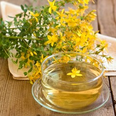 Herbal tea from Hypericum perforatum commonly known as St John's wort. Drink with fresh flowers on the wood table. Traditional herbal medicine.