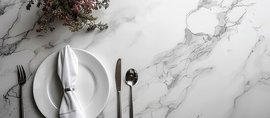 Poster - Top view of a chic dining arrangement with silverware and napkin on a white marble table alongside a designated copy space image