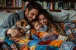 © Iurii - A family of three, a man, a woman, and a young child, cuddle under a colorful patchwork blanket on a couch in a cozy living room