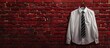 © Ilgun - Red brick wall showing a hanger with a white shirt and a striped tie providing copy space image