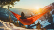 © Stefan - Man, a hiker lying in a hammock and looking at a beautiful mountain landscape with a sunrise or sunset, activity and enjoyment in nature, tourism and vacation, adventure and freedom, snow and hills,