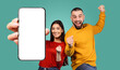 © Prostock-studio - A young couple celebrates their success with big smiles and excited gestures. The woman is holding a smartphone with a blank screen, while the man is raising his fist in the air.