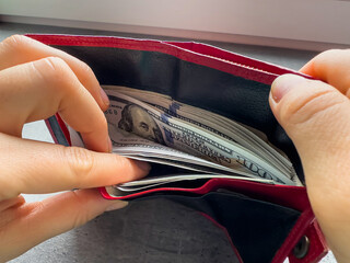 Wall Mural - woman takes out us dollar banknotes from a wallet. Rich businesswoman with money