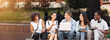© Prostock-studio - Campus Life. Cheerful college students resting outdoors between classes, using laptop, chatting and laughing, free space