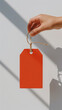 © wasan - A hand holding a vibrant red blank tag against a soft background, ideal for tagging products or gifts.