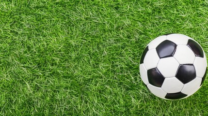 A black and white soccer ball lies on lush green grass, highlighting the perfect setting for a spirited game or practice session