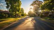 © Elmira - A deserted suburban street is illuminated by the warm golden light of the setting sun, casting long shadows and highlighting the tranquility of the neighborhood