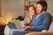 © Prostock-studio - Smiling Spouses Using Laptop Sitting Together On Couch Spending Weekend At Home. Selective Focus