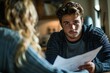 © Vera - Man intently discussing document with woman at home
