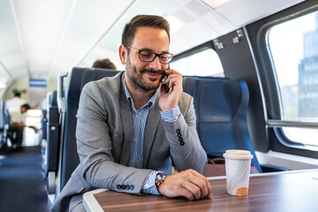 Businessman in train. Businessman working and traveling by train. He is using his smart phone. Young businessman talking by mobile phone in the train