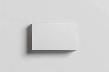 Poster - A pristine white rectangular box is captured as it casts a soft shadow on a blank wall, presenting an abstract yet modern minimalist piece, perfect for multiple purposes.
