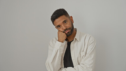 A contemplative young man with a beard poses against an isolated white background, exuding a casual yet handsome demeanor.