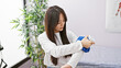 © Krakenimages.com - A young asian woman applies an ice pack to her arm in a modern clinic room, indicating a medical or physiotherapy context.