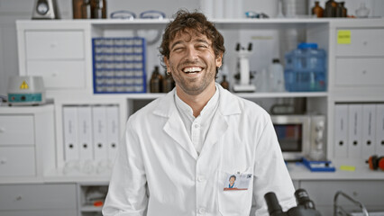 Wall Mural - Laughing bearded man in laboratory wearing labcoat posing for a joyful professional portrait