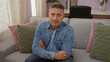 © Krakenimages.com - Handsome man sitting on a sofa in a cozy living room, looking directly at the camera