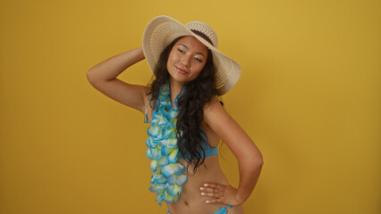 Wall Mural - Beautiful young asian woman in bikini and summer hat posing against a vibrant yellow background