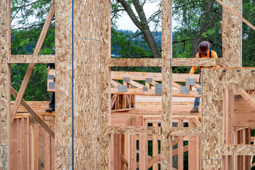 Wall Mural - Residential house construction, boom crane lifting lumber delivery, wood support truss beams, workman assisting in placement
