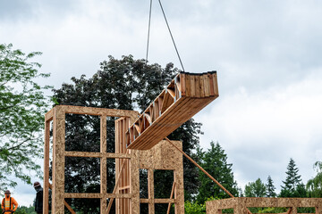 Wall Mural - Residential house construction, boom crane lifting lumber delivery, wood support truss beams, to next floor of in project
