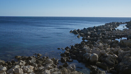 rocky shoreline with clear blue water and scattered boulders in gallipoli, puglia, salento, italy, u