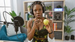 © Krakenimages.com - African american woman with braids in sports attire talking on a radio show indoors with a microphone and headphones.