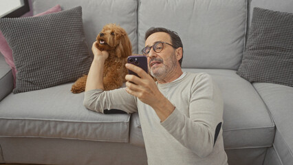 Poster - Hispanic mature man takes a selfie with his poodle in a cozy living room.