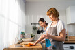 © Kawee - Caucasian senior elderly woman cleaning kitchen in house with daughter.