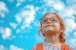 © kvladimirv - Joyful Child with Glasses Looking at Blue Sky with Clouds