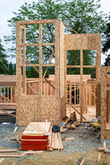 Wall Mural - New house construction in residential neighborhood, job site detail, wood house framing started, piles of delivered lumber and assorted small materials, ready for the workmen
