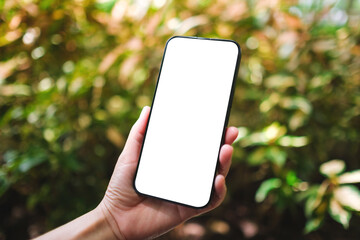 Wall Mural - Mockup image of a woman holding mobile phone with blank white desktop screen in the outdoors