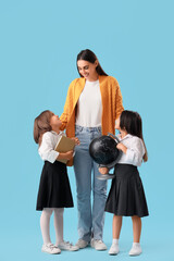 Wall Mural - Little school girls with female teacher on light blue background