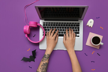 Woman with headphones, coffee cup and Halloween decor using laptop on purple background