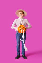 Canvas Print - Young man dressed for Halloween with pumpkin on color background