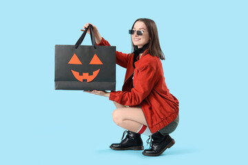 Wall Mural - Young woman with Halloween gift bag on blue background