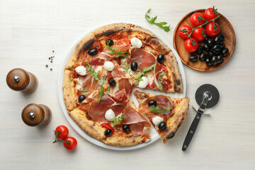 Wall Mural - Tasty pizza with cured ham, olives, mozzarella cheese, tomatoes and arugula on light wooden table, flat lay