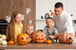 © Pixel-Shot - Happy family carving Halloween pumpkins in kitchen