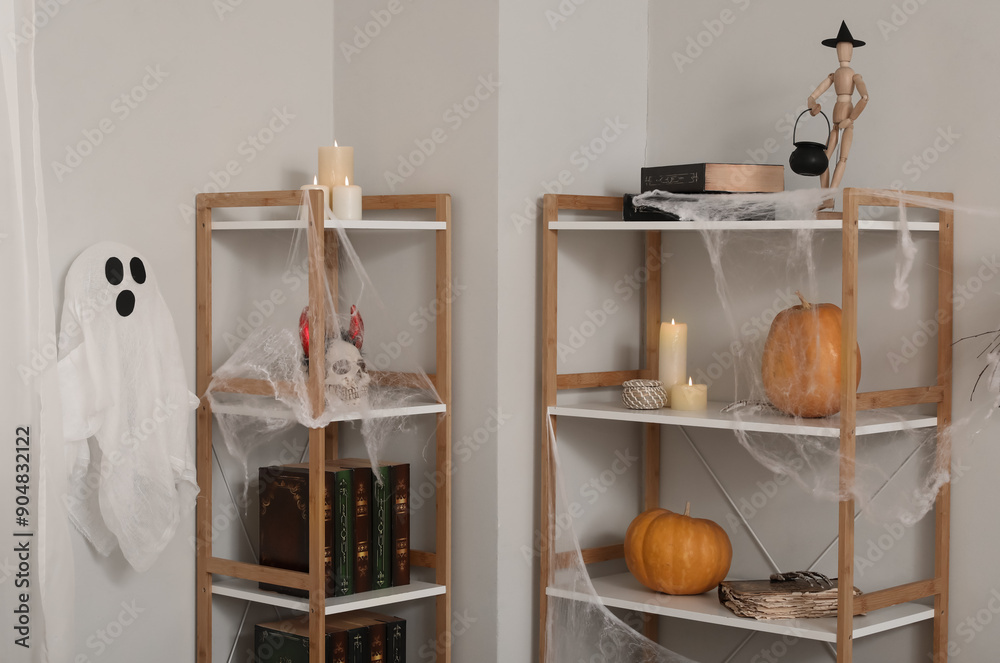 Shelf units with books, candles and Halloween decor in light room
