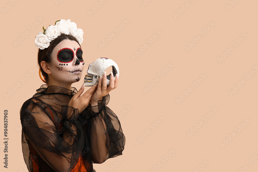 Young woman dressed for Halloween with painted skull on beige background