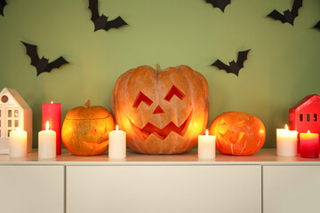 Wall Mural - Halloween pumpkins with burning candles on chest of drawers in room